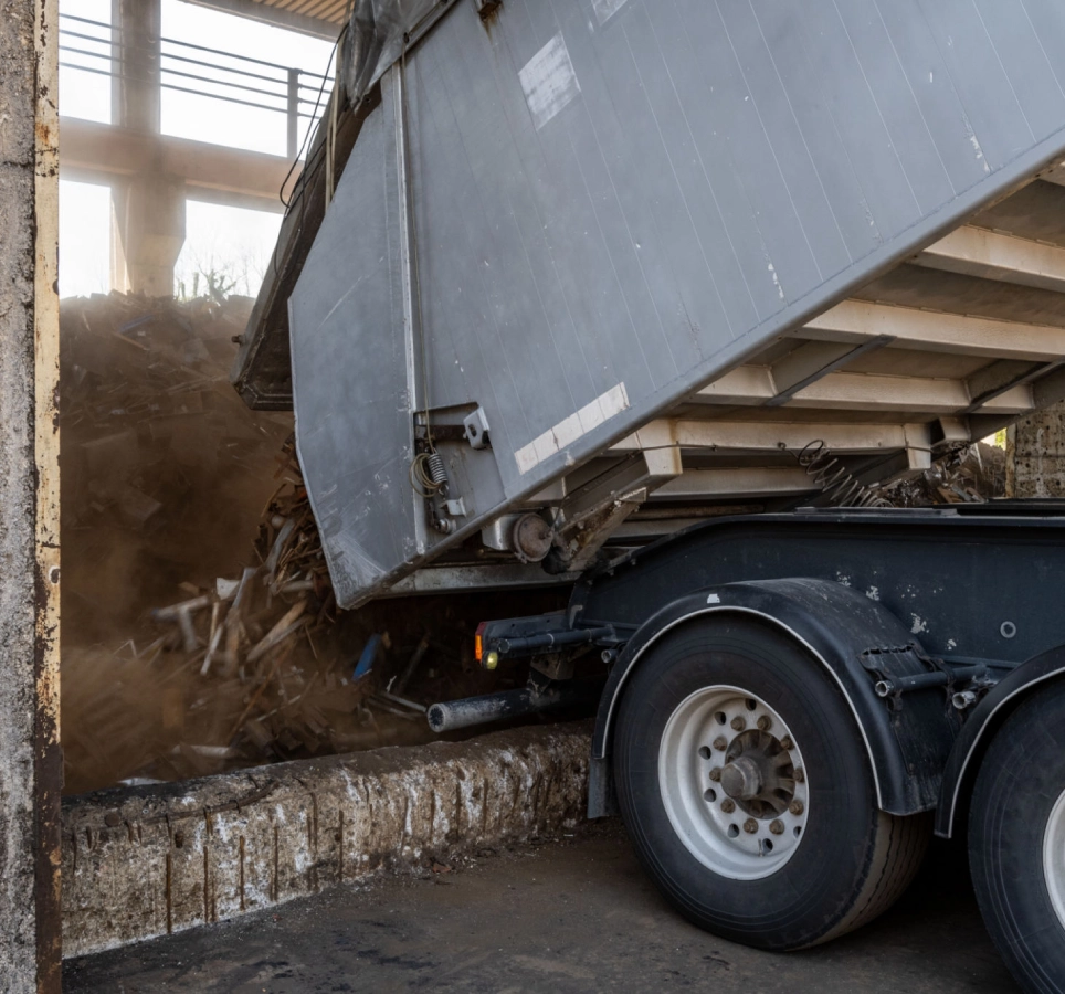 Truck unloading debris at waste facility.