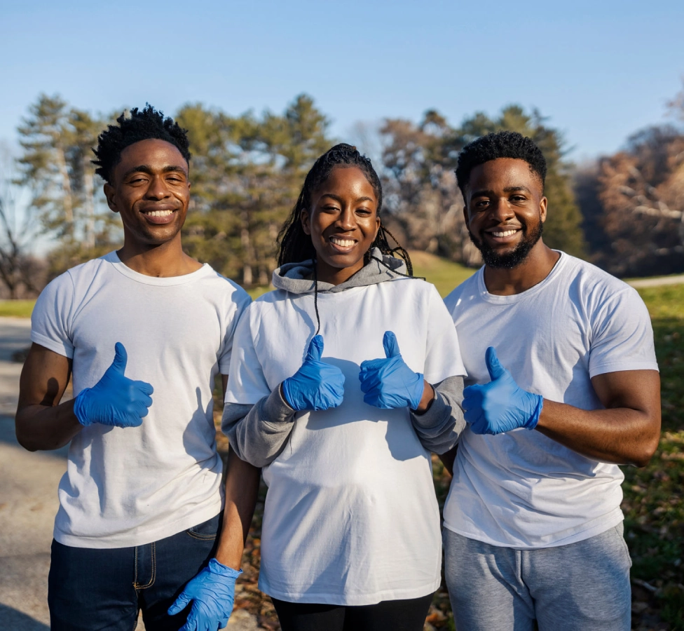 Three people outdoors giving thumbs up.